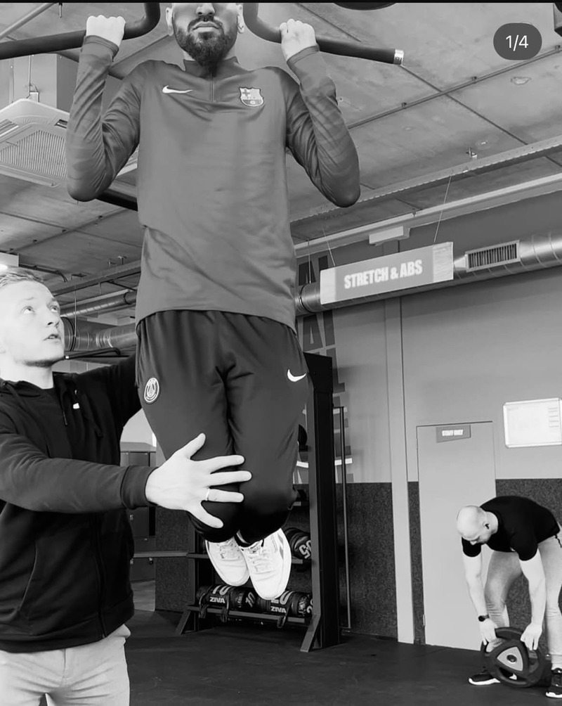 Personal trainer van Bluefit helpt cliënt met de juiste techniek bij pull up in de sportschool voor healthy ageing.